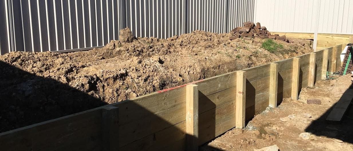 Treated pine timber sleeper retaining wall built along a cut batter at a Sydney property